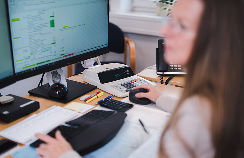 eine Mitarbeiterin der Kanzlei arbeitet am Computer, Blick über ihre Schulter